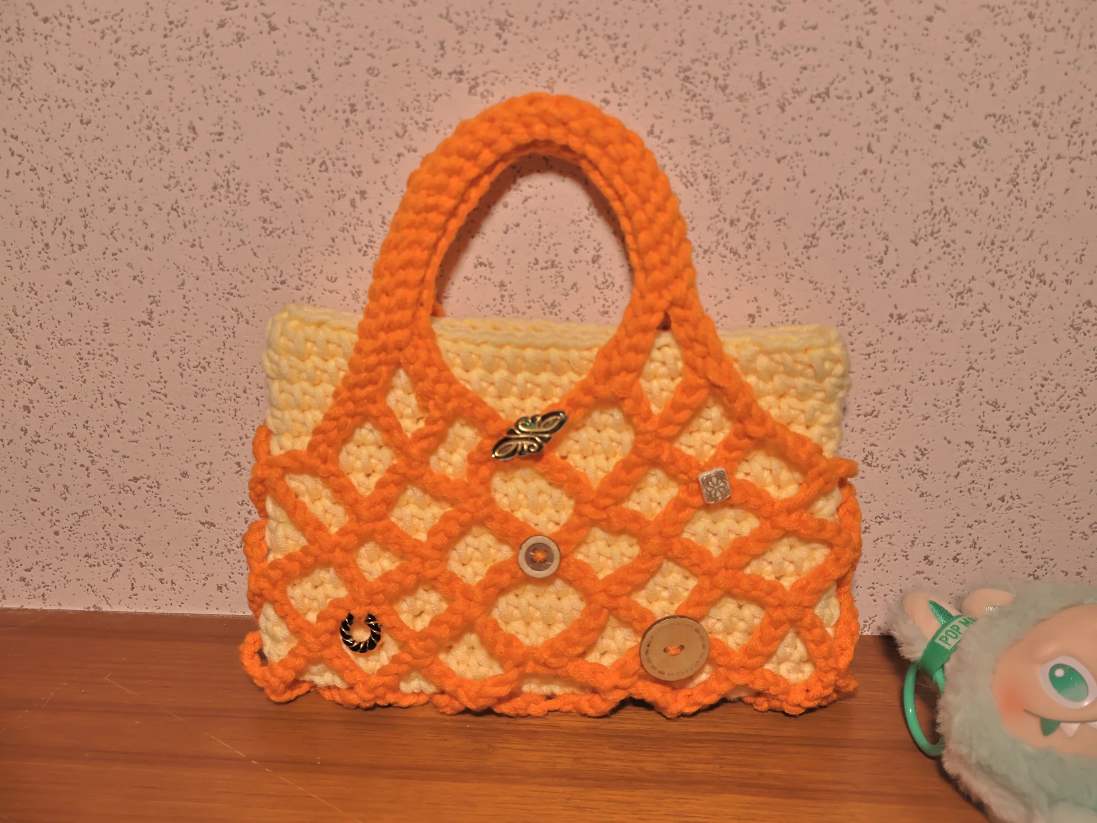 Orange lattice bag displayed with a playful studio object