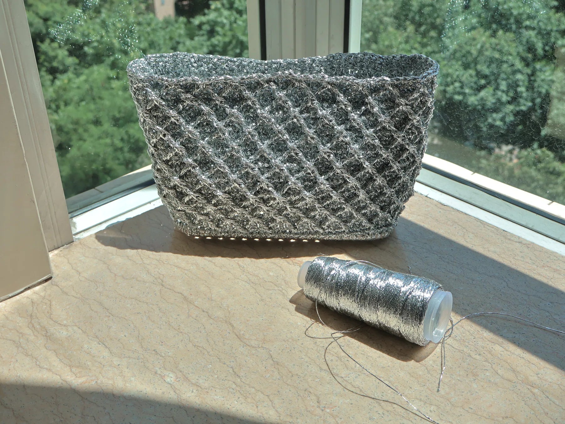 Silver lattice bag with thread spool and long window shadow